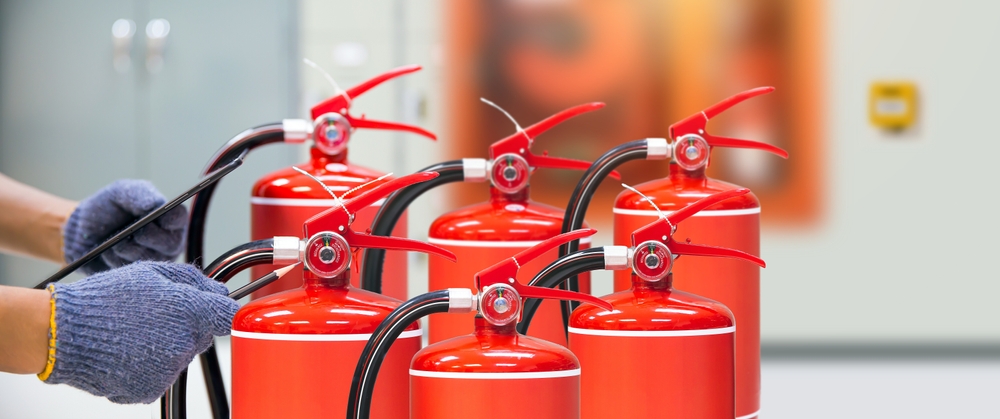 Gloved hand checking a row of fire extinguishers